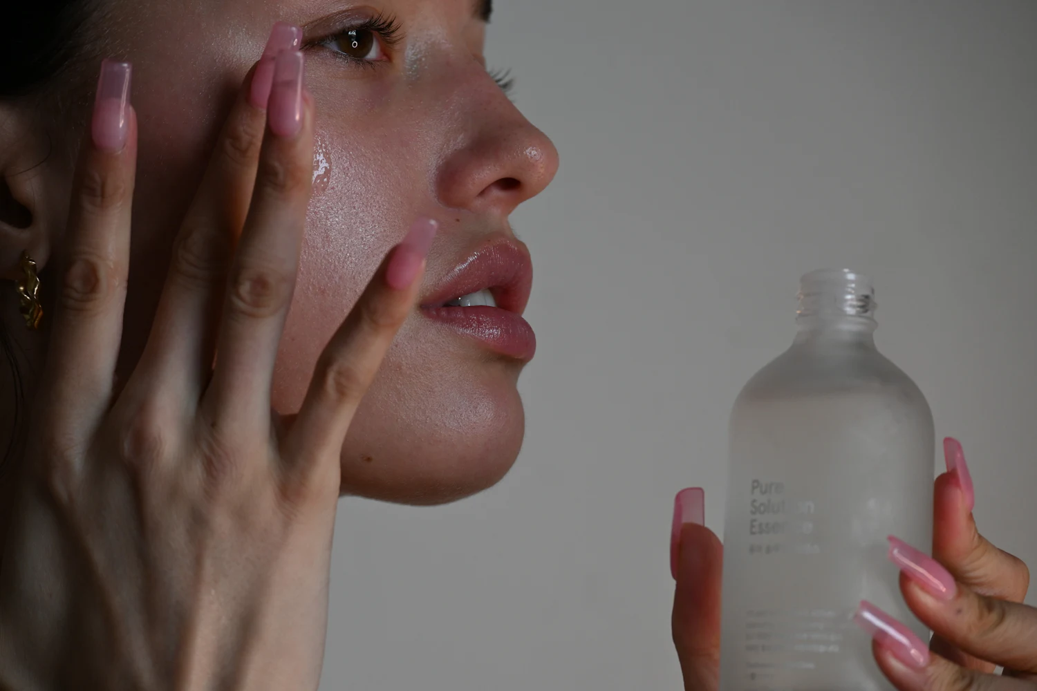 Persona aplicando sérum sobre la mejilla antes de completar su rutina facial.